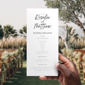 May include: A white wedding program with black text. The program lists the order of events for the wedding ceremony and reception. The names "Rosalie and Matthew" are written in a cursive font at the top of the program.