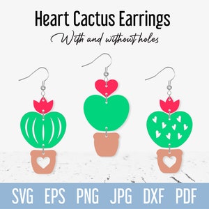 May include: Three pairs of heart cactus earrings, with and without holes. The earrings are made of green, pink, and white felt. The earrings are in the shape of a heart cactus with a flower on top. The earrings are hanging from silver hooks.