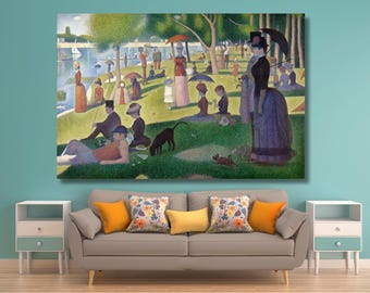 May include: A large rectangular canvas print featuring a pointillist painting of people relaxing in a park by a river. The scene includes figures in period clothing, umbrellas, trees, and a dog on a green lawn, displayed above a gray sofa with pillows.