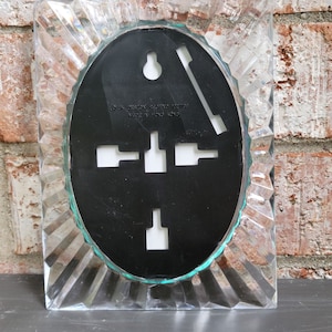 May include: A clear plastic picture frame with a beveled edge and a black oval insert. The insert has a hole for hanging and a label that reads "&copy;K. Design Reg'd No. 1001882 Made in Hong Kong."