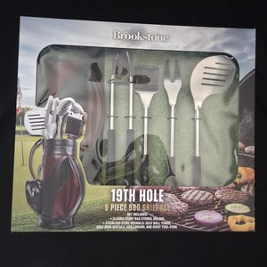 May include: A Brookstone 19th Hole 5-piece BBQ grill set in a box. The set includes a golf bag-shaped utensil holder, stainless steel golf ball tongs, a golf iron-shaped spatula, a grill brush, and a divot tool-fork with black handles.