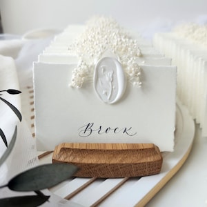 Deckled edge ivory place cards with dried flowers decor featuring elegant wax seal