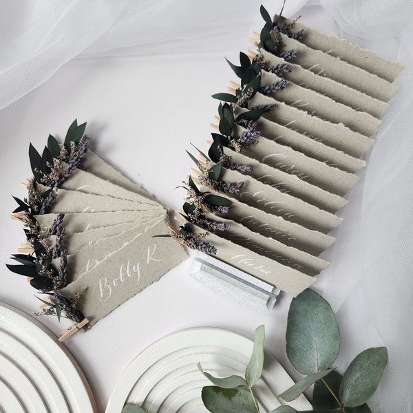 Craft gray wedding place cards with dried flowers decor. Handmade Deckled edge calligraphy place cards with dried eucalyptus and lavender.