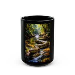 May include: Black ceramic coffee mug featuring a vibrant image of a large snake in a river. The snake is brown and yellow, and the river is surrounded by lush green trees. The mug is cylindrical and has a glossy finish.