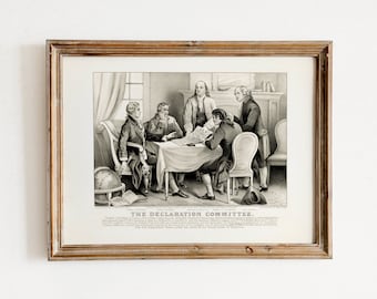 May include: A black and white print of a historical scene depicting five men seated around a table, working on a document. The text "THE DECLARATION COMMITTEE" is printed below the image. The print is framed in a light brown wood frame.