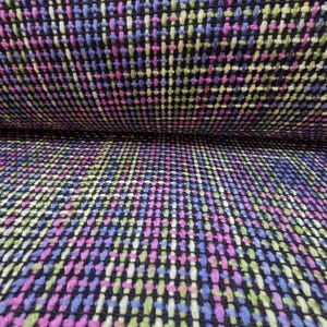 May include: A woven fabric featuring a dense grid pattern of black, bright pink, light blue, and lime green threads. The texture is visible with a cross-hatched weave structure where the dark base color is interspersed with vibrant colored yarns.