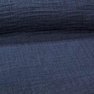 May include: Close-up of a folded section of navy blue fabric. The fabric has a textured weave, with visible horizontal and diagonal lines. The color varies slightly in tone, creating depth and shadow.