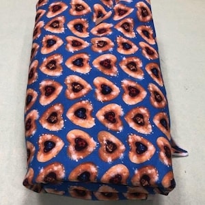 May include: Blue fabric with a repeating pattern of heart-shaped cookies with red and black filling. The fabric is folded in thirds.