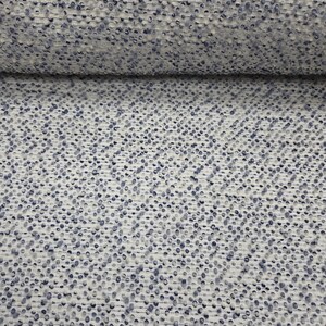 May include: A textured fabric featuring a dense pattern of small, raised blue dots evenly distributed across a white base. The material has a woven appearance with a consistent, repeating dotted design that creates a tactile surface texture.