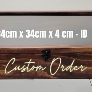 May include: A rectangular dark brown wooden display box with a clear glass lid and a black metal latch. The text 34cm x 34cm x 4 cm - ID is printed on the glass, and the words Custom Order are printed in yellow on the front wooden panel.
