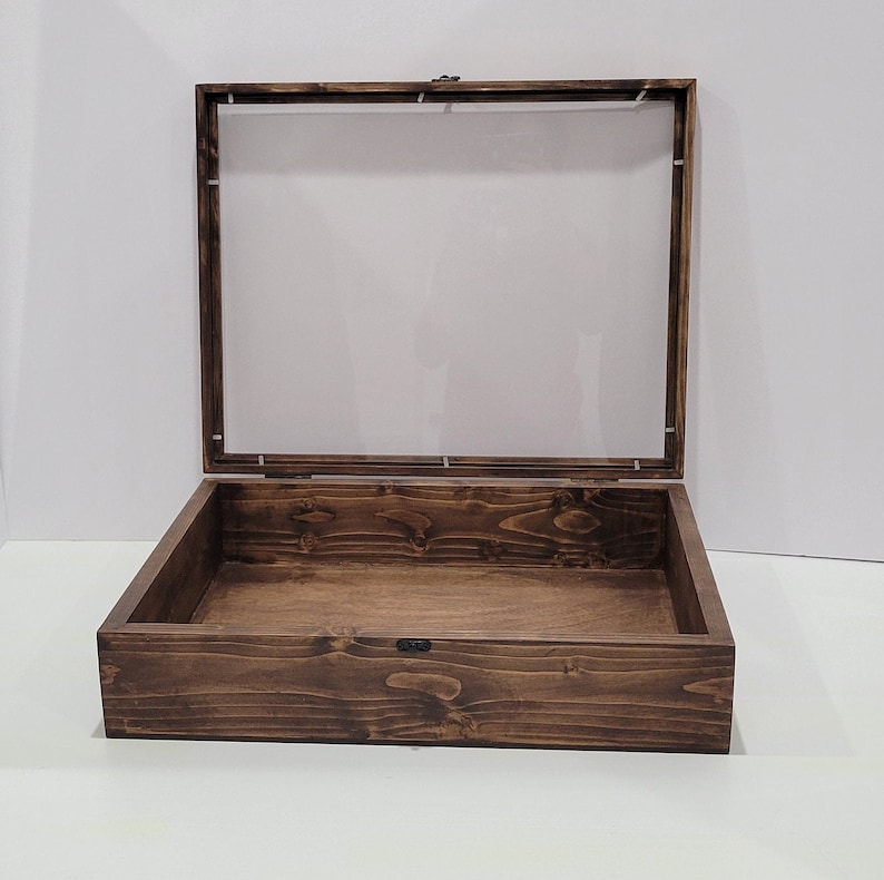 May include: A dark brown wooden display case with a clear glass top. The case is open and empty.