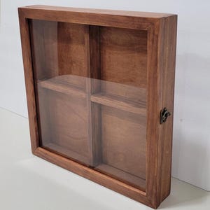 May include: A wooden display case with a glass front and four compartments. The case has a brown stain and a metal latch.