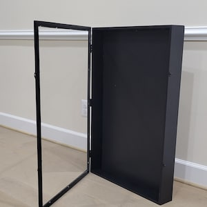 May include: A black framed display case with a glass door that is open. The case is empty.