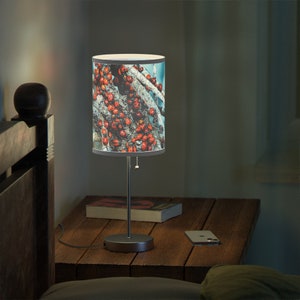 May include: A silver table lamp with a white drum shade featuring a colorful pattern of red ladybugs on a blue background.