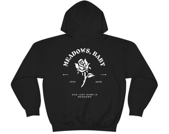 May include: Black hooded sweatshirt with a white graphic design on the back. The graphic features a rose with the text "Meadows, Baby" above it and "Little Mouse" below it. The text "Our Last Name is Meadows" is below the rose.