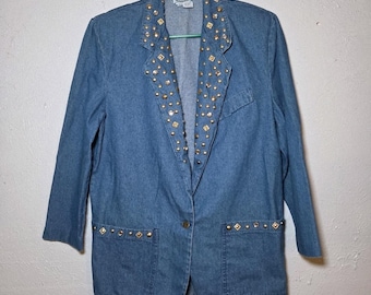 May include: A medium-wash denim blazer with gold-colored stud embellishments on the lapels, pockets, and shoulders. The blazer has a single-button closure and two front pockets. The sleeves are three-quarter length.