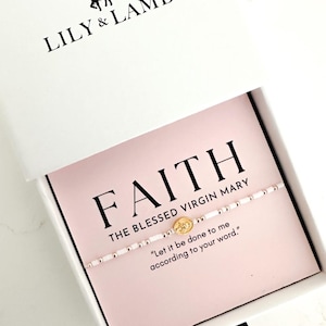 May include: A white gift box containing a beaded bracelet on a light pink card. The card features the text FAITH, THE BLESSED VIRGIN MARY, and Let it be done to me according to your word. The bracelet has white beads and a small gold-toned charm.