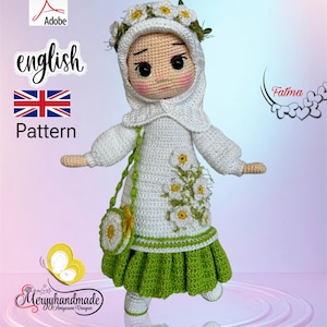 Può includere: Bambola amigurumi all'uncinetto che indossa un vestito bianco con una gonna verde e un velo bianco con una corona di fiori. La bambola tiene una piccola borsa bianca con un motivo a margherita. La bambola è in piedi su uno sfondo blu chiaro.