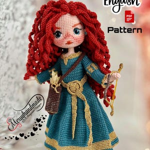 Op de afbeelding: Handgemaakte gehaakte pop met rood krullend haar, blauwe ogen en een blauwgroene jurk met gouden accenten. De pop houdt een pijl en boog en een koker vast. De tekst "English Pattern" is inbegrepen.