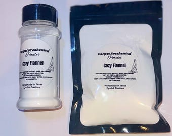 May include: Two containers of carpet freshening powder, one in a clear jar with a black lid and the other in a white resealable bag with a black border. Both containers have a label that reads "Carpet Freshening Powder Cozy Flannel" and instructions for use. The label also states "Handmade in Texas Kyndals Kreations".