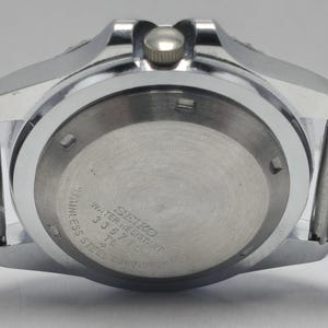 May include: Close-up of a stainless steel Seiko watch. The watch back features the text "SEIKO WATER RESISTANT" and other details. The watch has a silver-colored metal band and a silver-colored case.