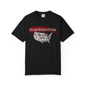 May include: A black short-sleeve t-shirt featuring a graphic of the United States map filled with a collage of small black and white photographs. Above the map is a red brushstroke design with the white text DAHMERNATION printed across it.