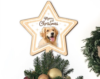 May include: A Christmas tree decorated with red and gold ornaments, pine cones, and white lights. The tree is topped with a wooden star featuring a golden retriever dog and the text "Merry Christmas".