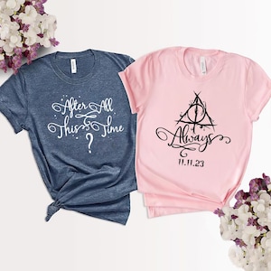 May include: Two t-shirts, one blue and one pink, with text and a graphic. The blue shirt says "After All This Time?" and the pink shirt says "Always" with a symbol of a triangle with a circle inside and the date "11.11.23".
