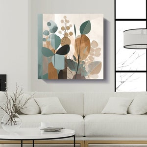 May include: Abstract art print featuring a stylized floral design with brown, green, and blue colors. The print is framed and hanging on a white wall above a white couch.