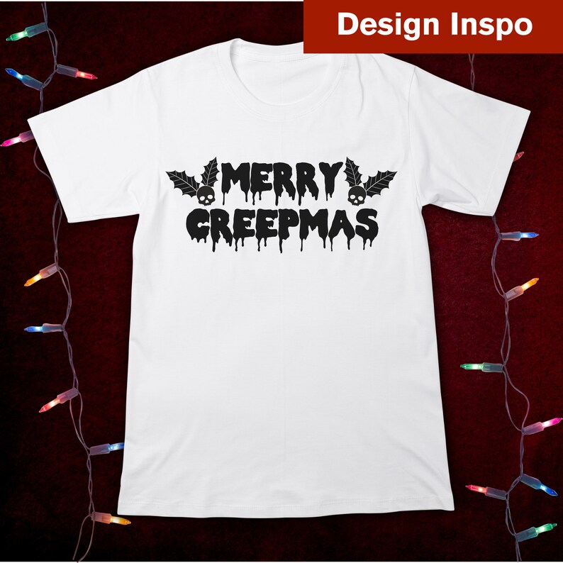 May include: White t-shirt with black text that reads "Merry Creepmas" with dripping letters and skulls on either side of the word "Merry".