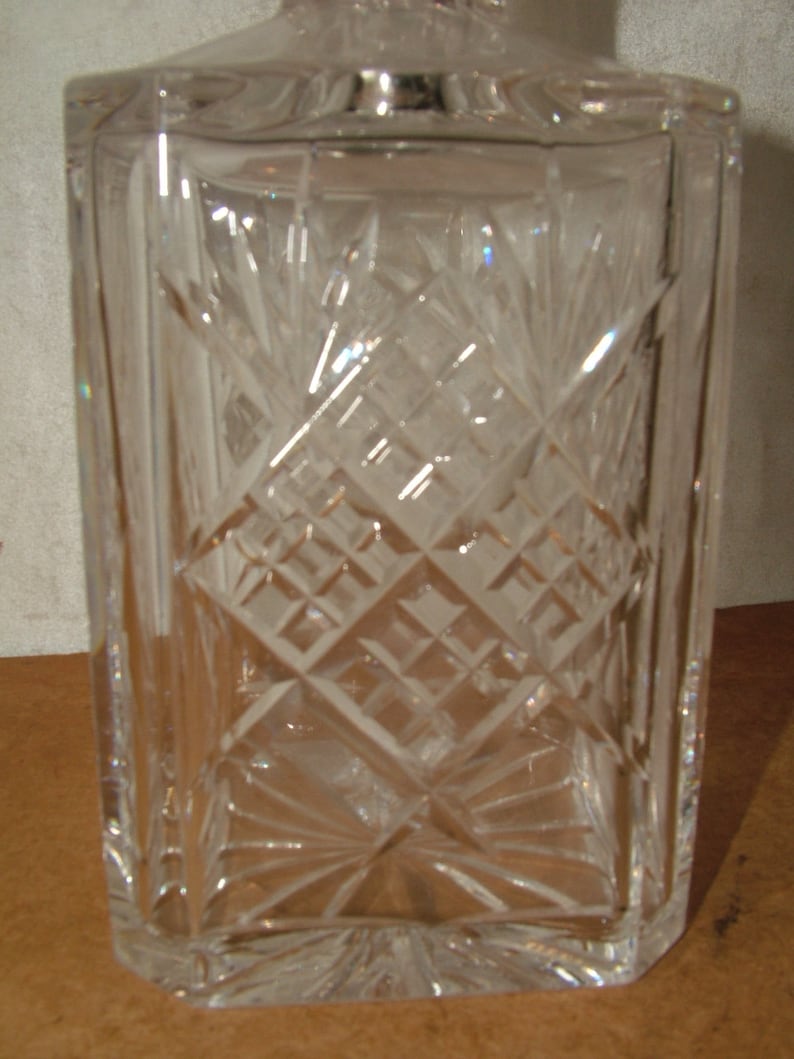May include: A clear glass decanter with a square body and a diamond-shaped pattern etched into the glass.