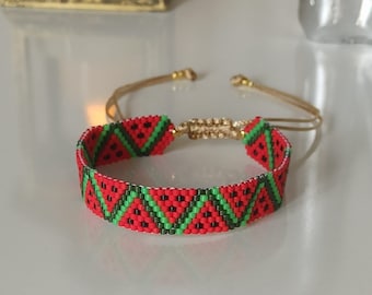 May include: A red and green beaded bracelet with a watermelon pattern. The bracelet is made with small beads and has a simple design.