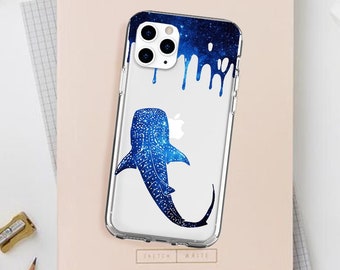 May include: A clear phone case with a blue whale shark design. The shark is silhouetted against a blue and white starry sky. The case has a dripping paint effect.