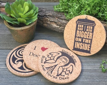 May include: Four cork coasters with different designs. One coaster features a TARDIS with the text "BIGGER ON THE INSIDE". Another coaster has a stylized angel with the text "DON'T BLINK AND YOU'RE DEAD". A third coaster has a heart with the text "I Doc". The fourth coaster has a swirling design.