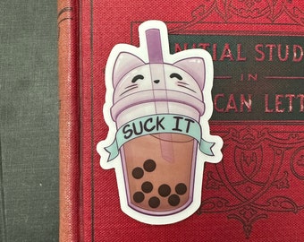 May include: A sticker of a purple and white cat-shaped boba tea cup with the text "SUCK IT" on a green ribbon. The cup is filled with brown boba tea and has black boba pearls.