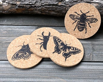 May include: Set of four cork coasters featuring black and white insect illustrations. The coasters feature a bee, a butterfly, a moth, and a stag beetle.