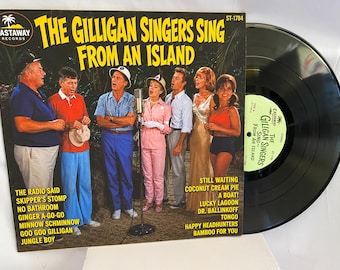 Op de afbeelding: Een vinylplaat getiteld The Gilligan Singers Sing From An Island van Castaway Records. De hoes toont een groep mensen in kleurrijke kleding die bij een microfoon staan. De tracklist bevat nummers zoals Skipper's Stomp en Tongo.
