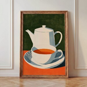 Op de afbeelding: Een ingelijste kunstprint met een witte theepot en een bijpassend theekopje gevuld met oranje vloeistof op een schoteltje. De achtergrond is verdeeld in een donkergroen bovengedeelte en een feloranje ondergedeelte, met een gestreept patroon op het schoteltje.