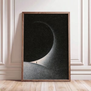 Può includere: Una stampa artistica da parete rettangolare incorniciata che presenta un'illustrazione in bianco e nero ad alto contrasto di una figura solitaria in piedi su un paesaggio curvo e strutturato sotto una grande forma scura a mezzaluna.