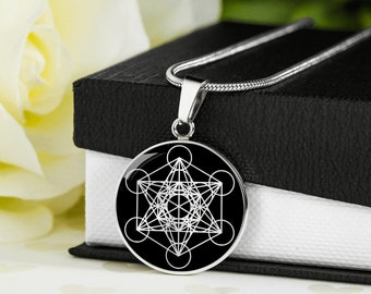 May include: A silver necklace with a black round pendant featuring a white geometric design. The pendant is a sacred geometry symbol, the Metatron's Cube.