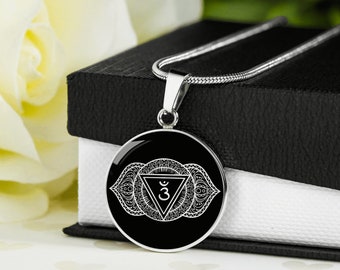 May include: A silver necklace with a black and white pendant featuring a third eye symbol and intricate mandala design.