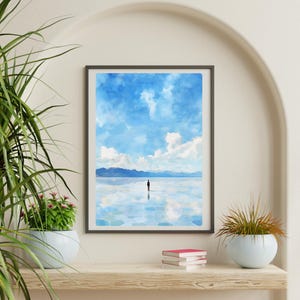 May include: A framed watercolor painting of a person standing in a body of water with a blue sky and white clouds in the background.
