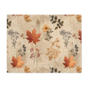 Puede incluir: Cojín rectangular con un estampado vintage de otoño. El diseño presenta ilustraciones en acuarela de hojas de otoño, flores y elementos botánicos en tonos naranja, amarillo y marrón, sobre un fondo de papel envejecido con escritura.