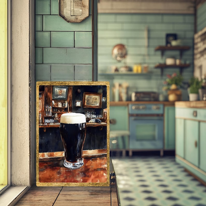 May include: A framed watercolor painting of a pint of dark stout beer with a thick, creamy head. The artwork depicts a pub scene with a bar and bottles. The frame is gold-colored, and the background is a kitchen.