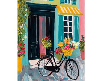 May include: An artistic print depicts a charming European street scene. A black bicycle with a yellow basket filled with flowers and baguettes is parked in front of a building with a teal door and shutters, and a yellow awning. Pink and yellow flowers are in pots.