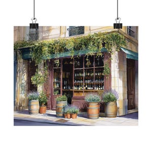 May include: Watercolor print of a Parisian wine shop. The shop features a dark wood facade, a green awning, and a display of wine bottles. Wooden barrels with lavender plants sit outside. The building is painted in warm tones.