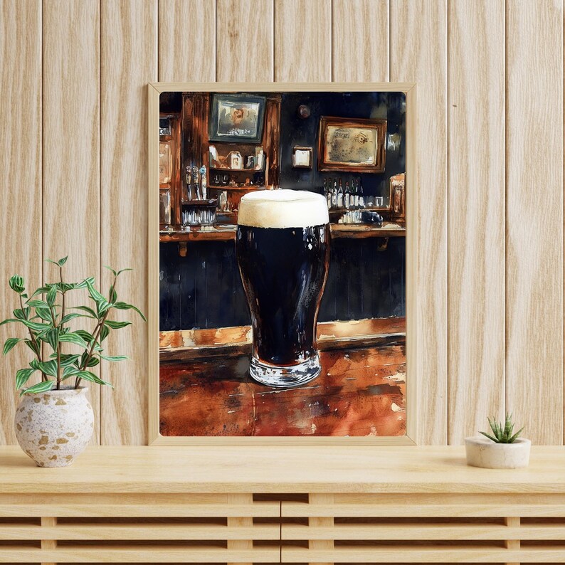 May include: Watercolor painting of a pint of dark stout beer with a thick, creamy head, set in a traditional pub scene. The artwork features a wooden bar, bottles, and framed pictures, creating a cozy atmosphere. The painting is in a wooden frame.