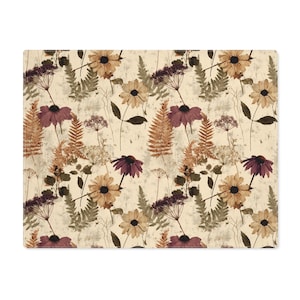 May include: A rectangular placemat featuring a floral pattern. The design includes various flowers in shades of burgundy, tan, and brown, along with fern leaves, set against a cream-colored background. The overall aesthetic is reminiscent of a vintage botanical print.