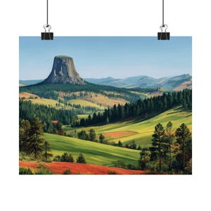 May include: A landscape print depicting a distinctive rock formation amidst green hills and forests. The artwork uses a vibrant colour palette with greens, browns, and blues. The print is suspended by black clips, offering a ready-to-hang display.