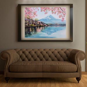 Peut inclure: Peinture &agrave; l'aquarelle d'un paysage japonais avec le Mont Fuji, des fleurs de cerisier et un lac. L'&oelig;uvre est encadr&eacute;e dans un cadre marron fonc&eacute; et est suspendue au-dessus d'un canap&eacute; touffet&eacute; marron. La peinture repr&eacute;sente une sc&egrave;ne sereine avec des couleurs douces.